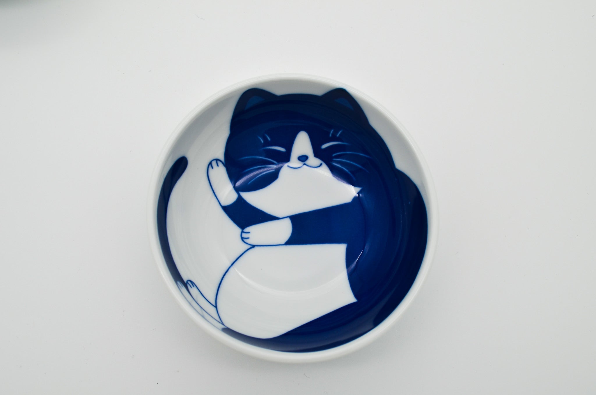 Ceramic plate with a blue and white cat design on a light gray background
