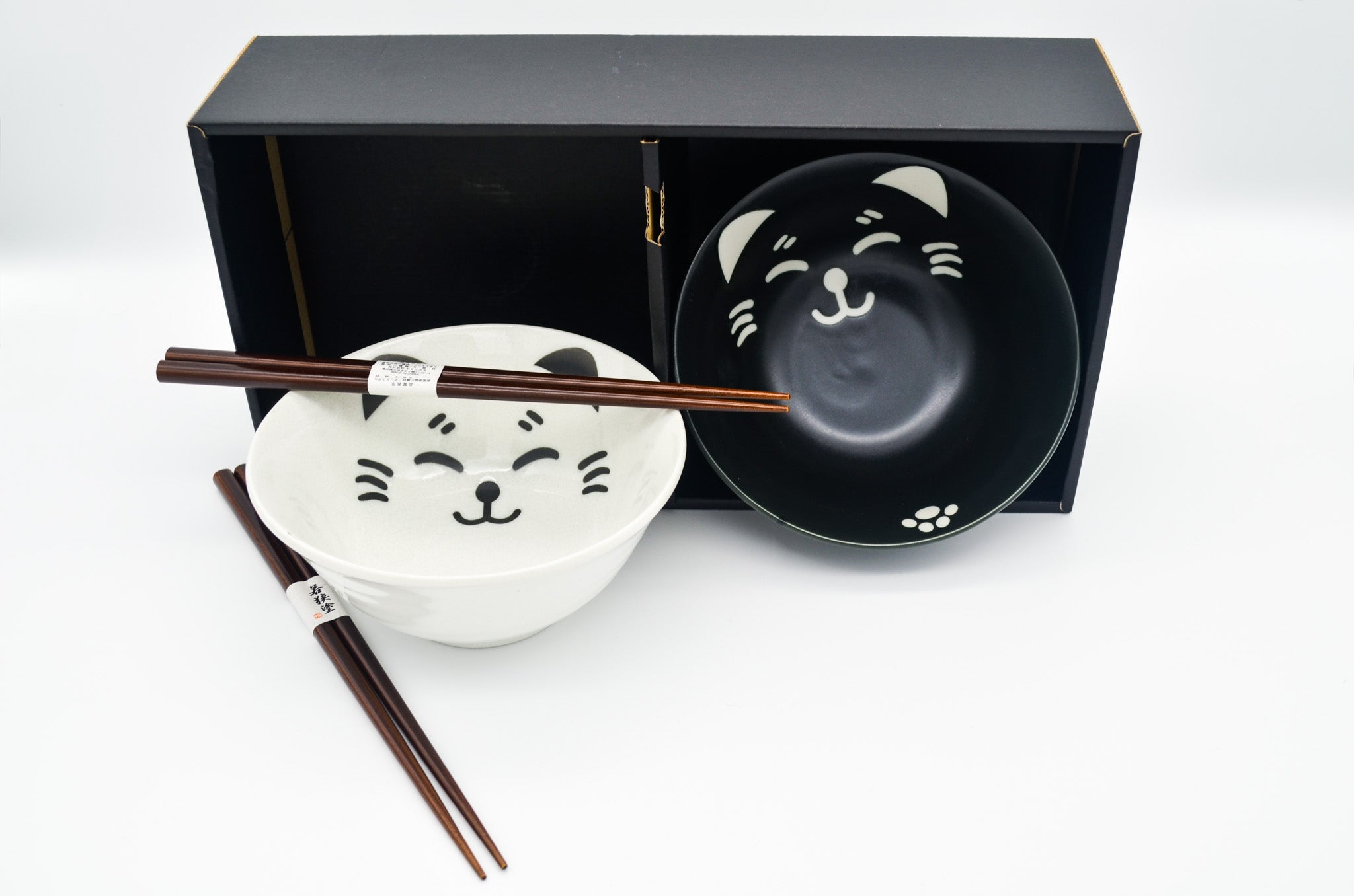 Two ceramic bowls with cat designs and chopsticks on a white background