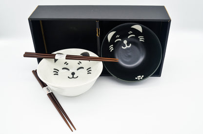 Two ceramic bowls with cat designs and chopsticks on a white background
