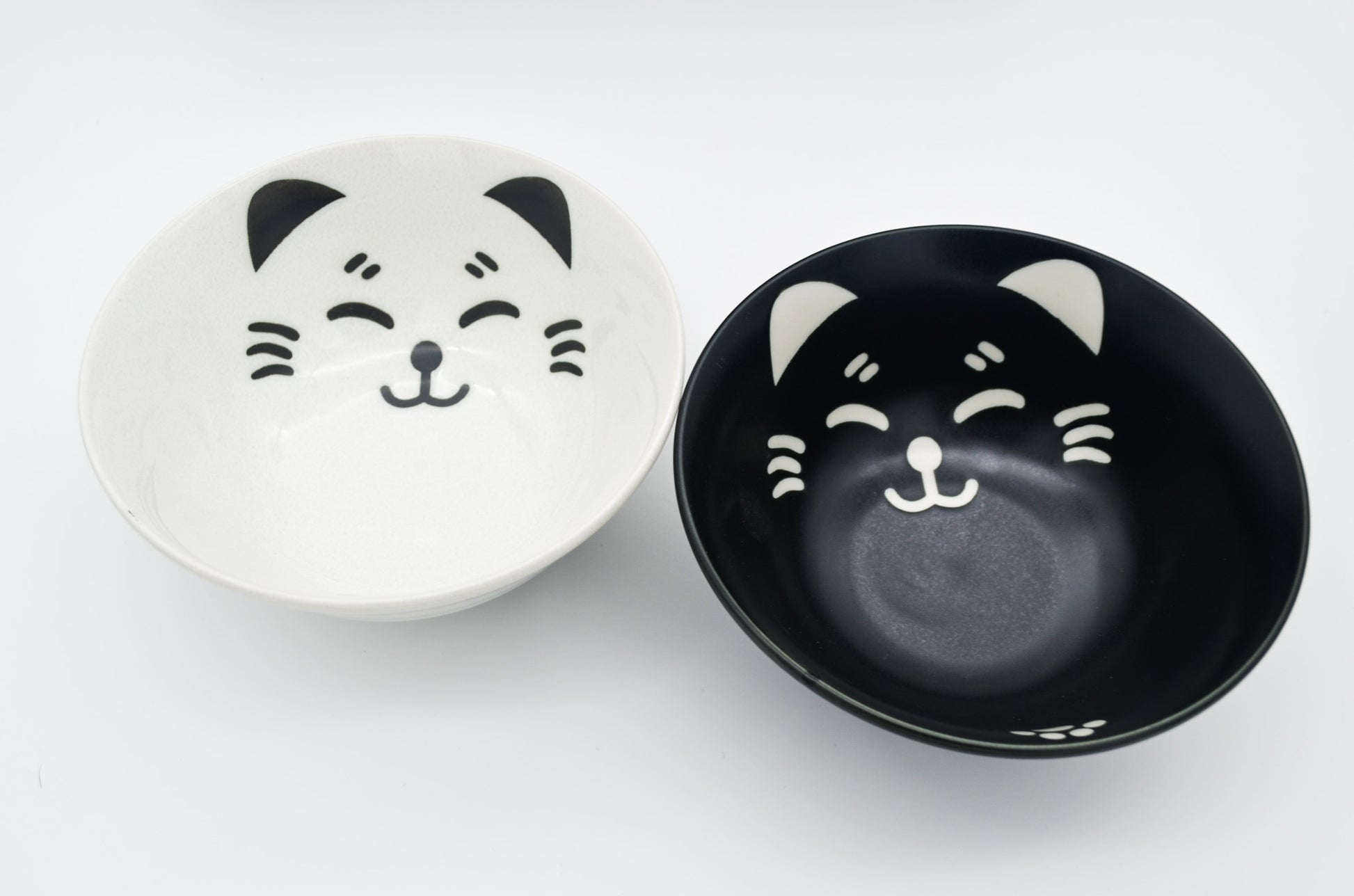 Two ceramic bowls with cat face designs on a white background