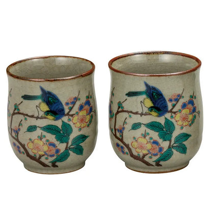 Two ceramic cups with bird and floral design on a white background