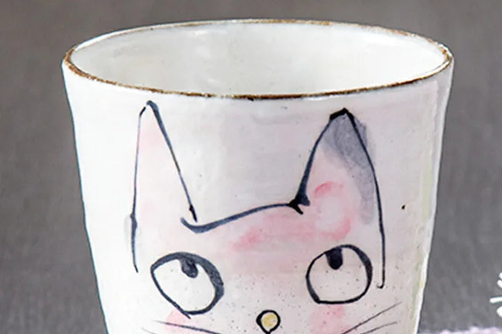 Ceramic mug with a cat face design on a gray background