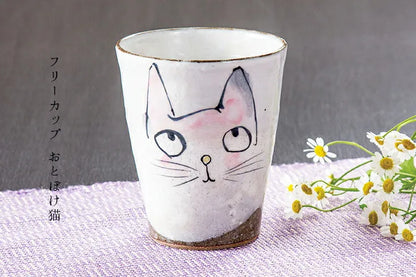 Ceramic cup with a cat design on a textured surface with flowers.