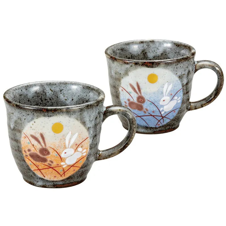 Two ceramic mugs with rabbit and full moon designs on a white background