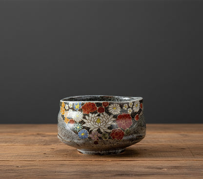 Decorative ceramic bowl with floral patterns on a wooden surface and dark background