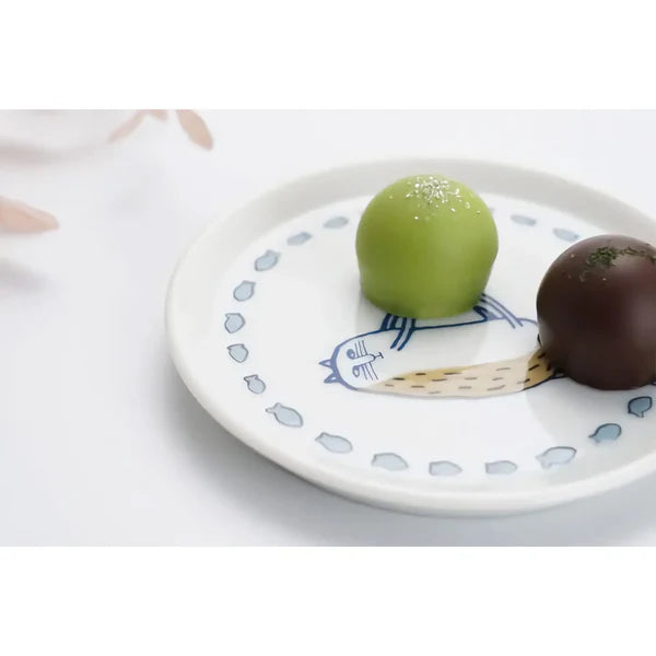 Two spherical desserts, one green and one chocolate, on a decorative plate with a white background.