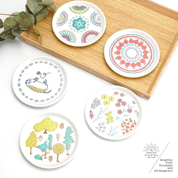 Set of five decorative plates with colorful patterns on a wooden board.