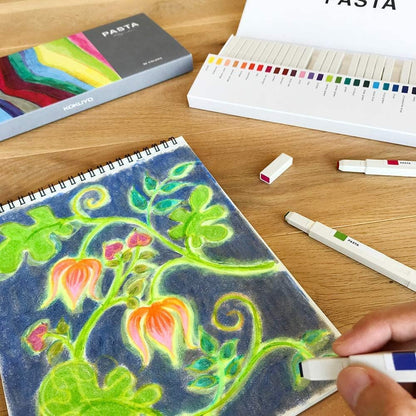 Colorful drawing of plants on a notebook with markers and color chart on a wooden table.