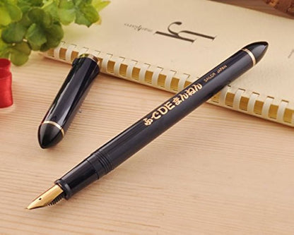 Black fountain pen with gold accents on a wooden surface next to a notebook