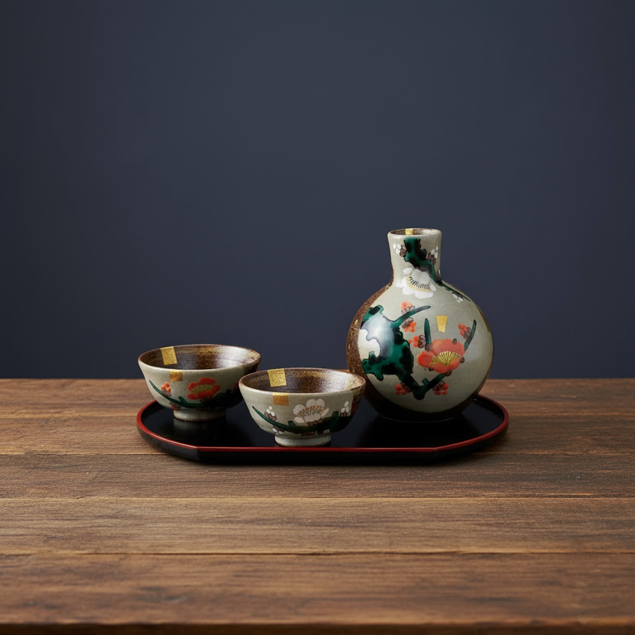 Set of ceramic items including a bottle and two cups on a wooden table with a dark background