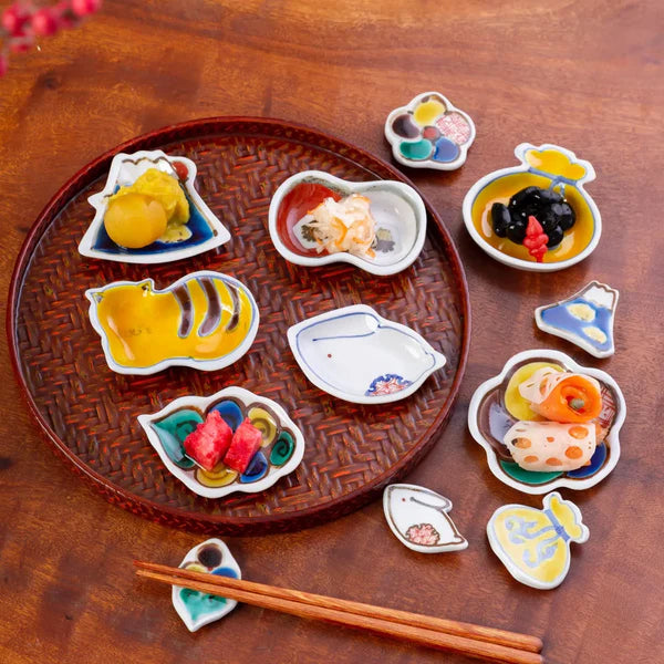 Set of small ceramic dishes with food illustrations on a wooden tray