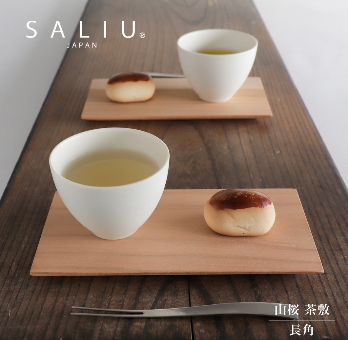 Two white ceramic cups with tea and bread on wooden trays, featuring the brand 'SALIU Japan'.