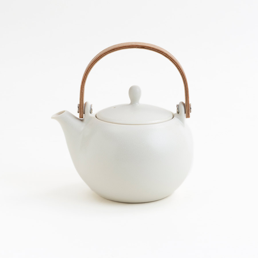 White teapot with a bronze handle on a white background