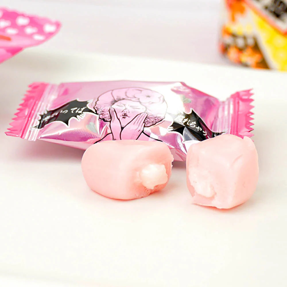 Pink candy with a decorative wrapper on a white surface